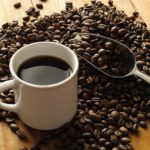 Cup of coffee surrounded by coffee beans